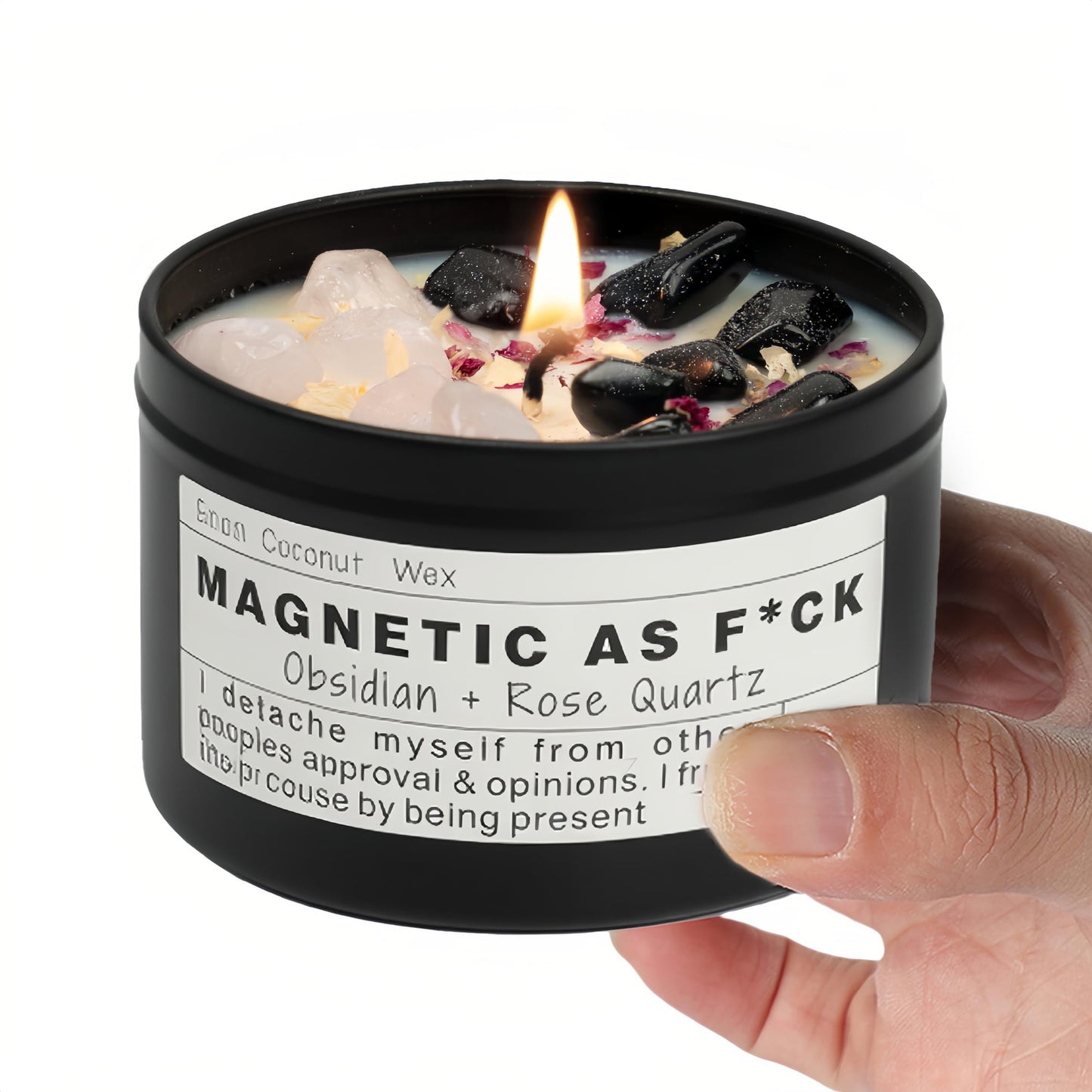 Magnetic As F*ck candle with obsidian and rose quartz crystals held in a hand against a white background.