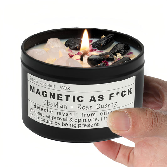 Magnetic As F*ck candle with obsidian and rose quartz crystals held in a hand against a white background.