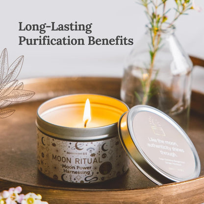 Moon Ritual scented candle in a decorative tin with the lid open, burning on a wooden tray with flowers and a glass vase in the background.